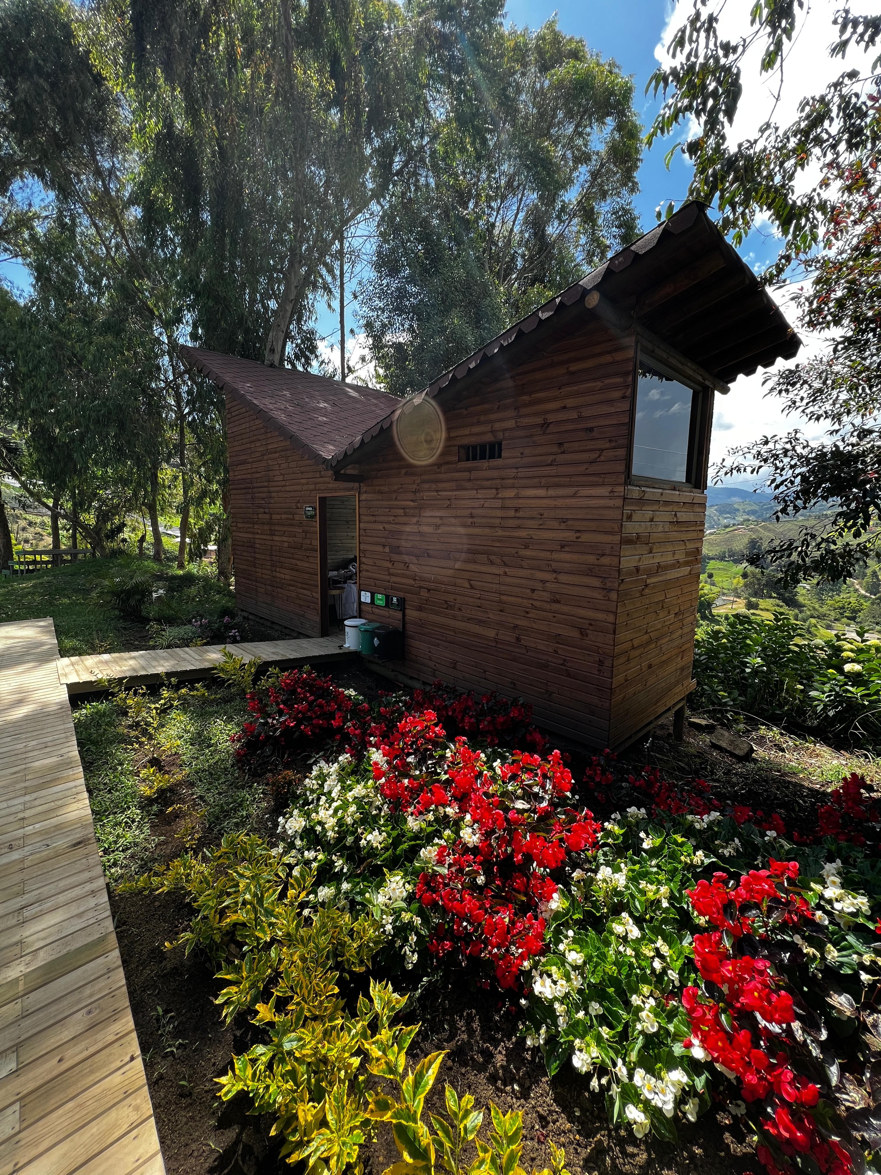 Cabaña con jardín de flores rojas y pasarela