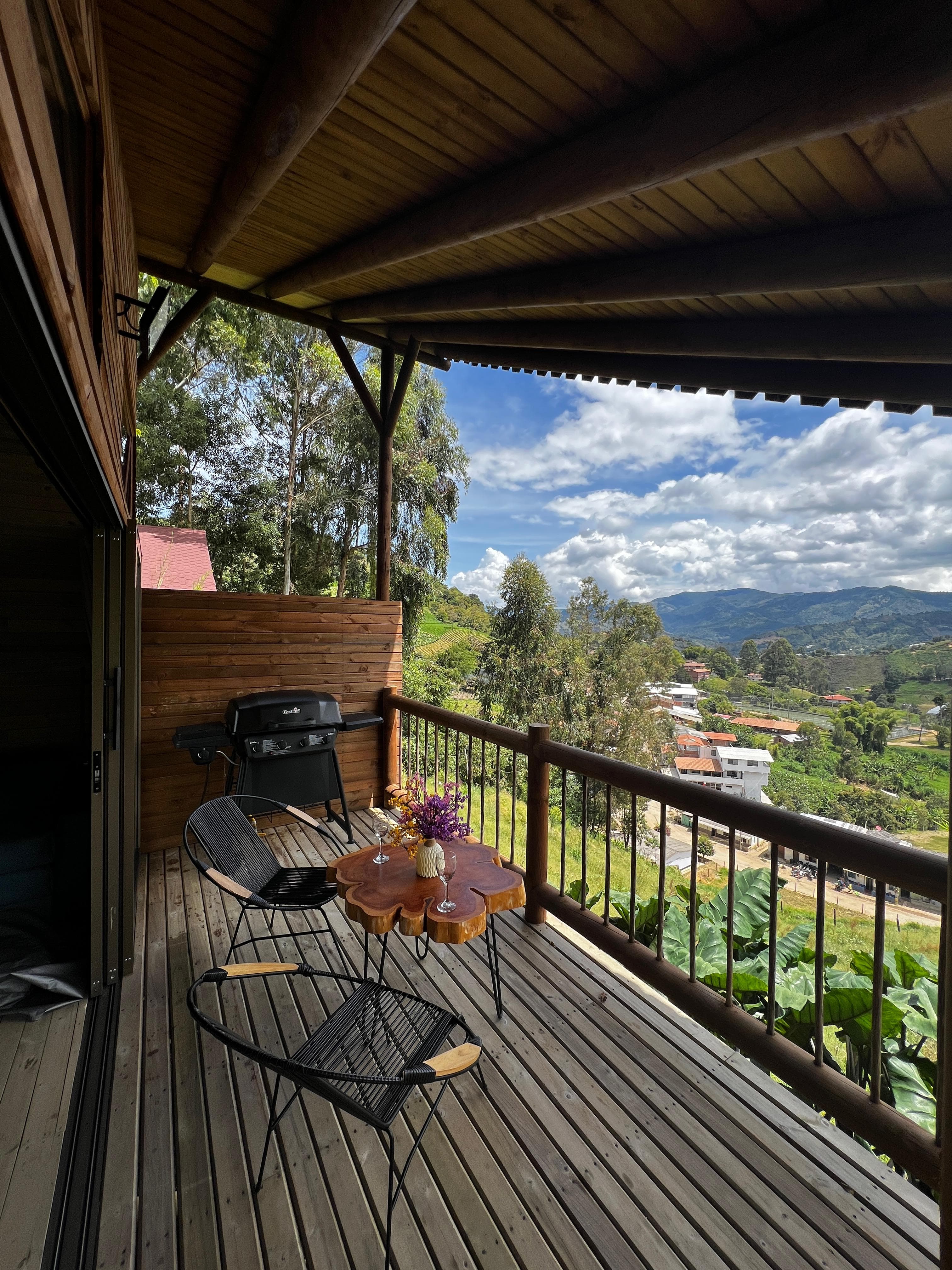 Terraza cubierta con sillas negras y BBQ